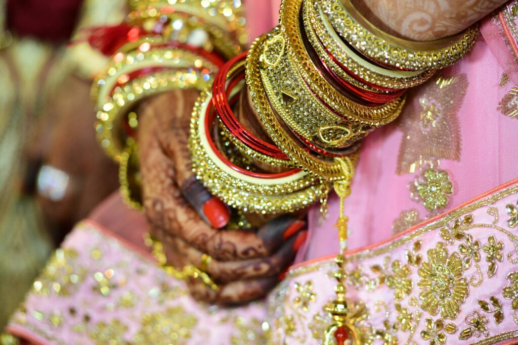 Close-up of a bride's hands adorned with intricate henna and traditional jewelry during an Indian wedding.