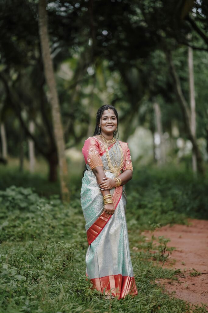 Portrait of an Indian bride in a saree amidst lush greenery, showcasing traditional attire.