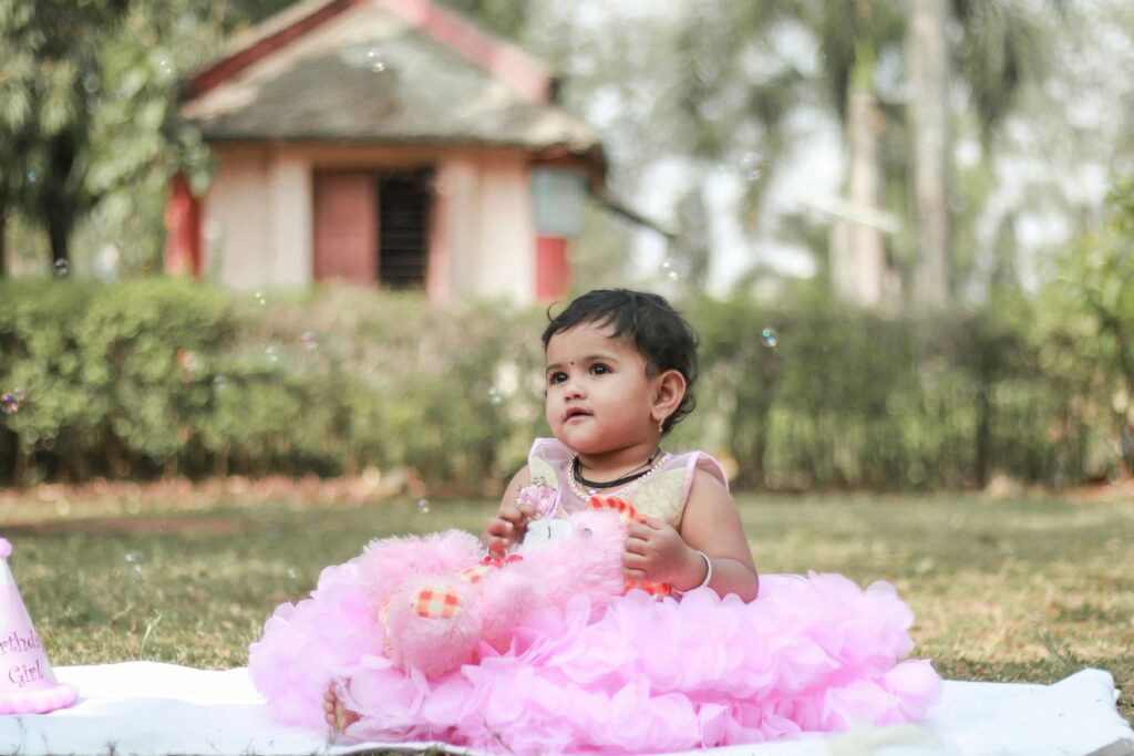 Charming baby girl in a pink dress enjoying a sunny day in an Indian garden.